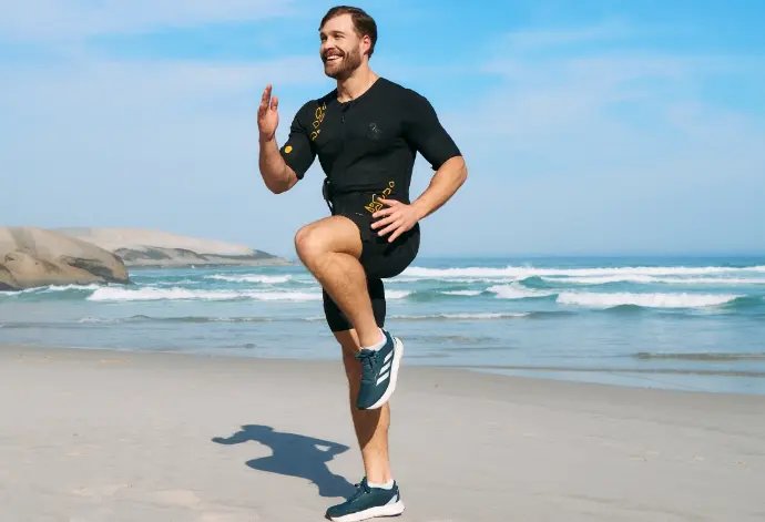 A man in an EMS suit trains outdoors on the beach, engaging in an effective and intense workout to reduce fat and support weight loss with EMS.